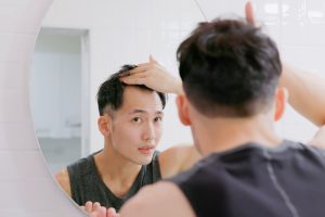 man looking at receding hair line in the mirror